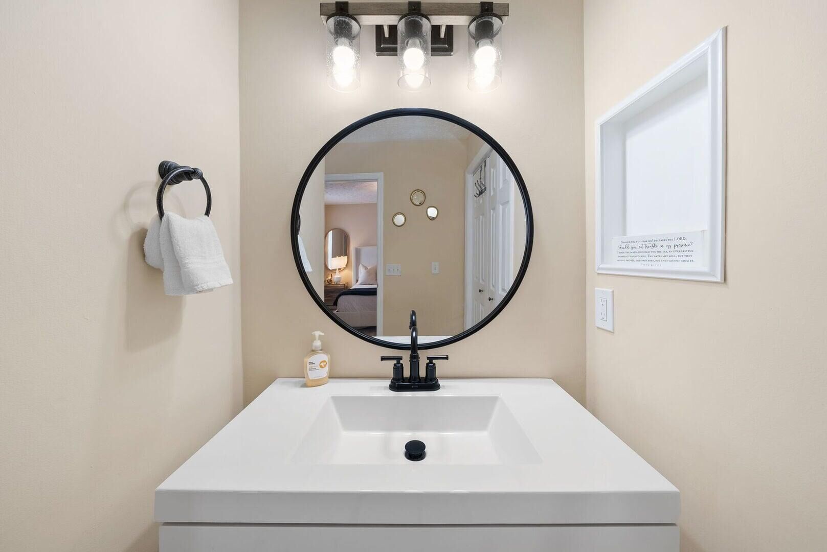 A bathroom with a white sink, a round mirror, and a towel rack.