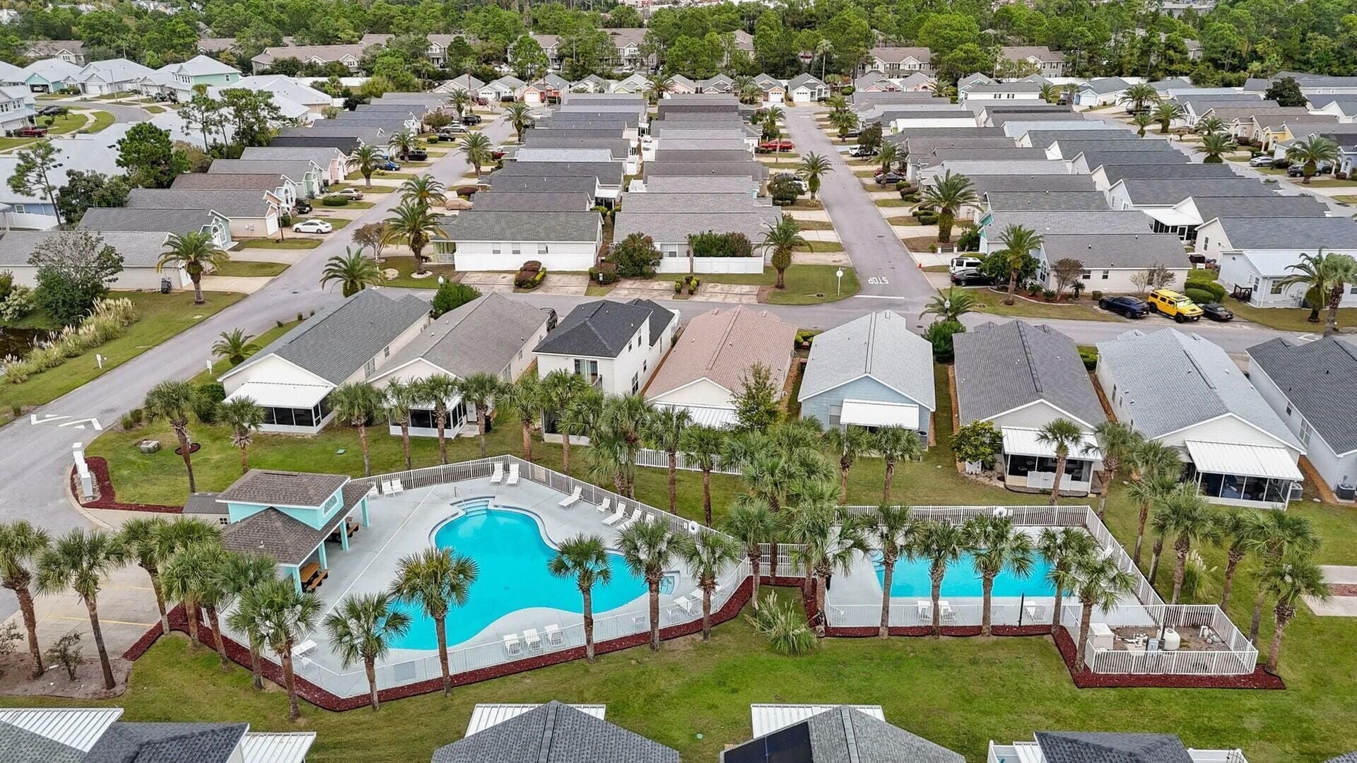 Un barrio residencial con varias casas, una piscina y palmeras.