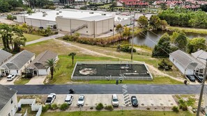 A residential area with a large building, a fenced sports court, and a river. - Pet Friendly | Mid-Term & Snowbird Friendly | Near Beach | Central PCB (Panama City Beach)