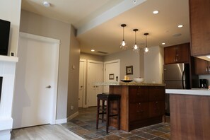 A modern kitchen with a central island, pendant lighting, and a stainless steel refrigerator. - Magnificent Mountain View/2BR/2BA with AC/Hot tub/GYM/Sona/Free Parking (Canmore)