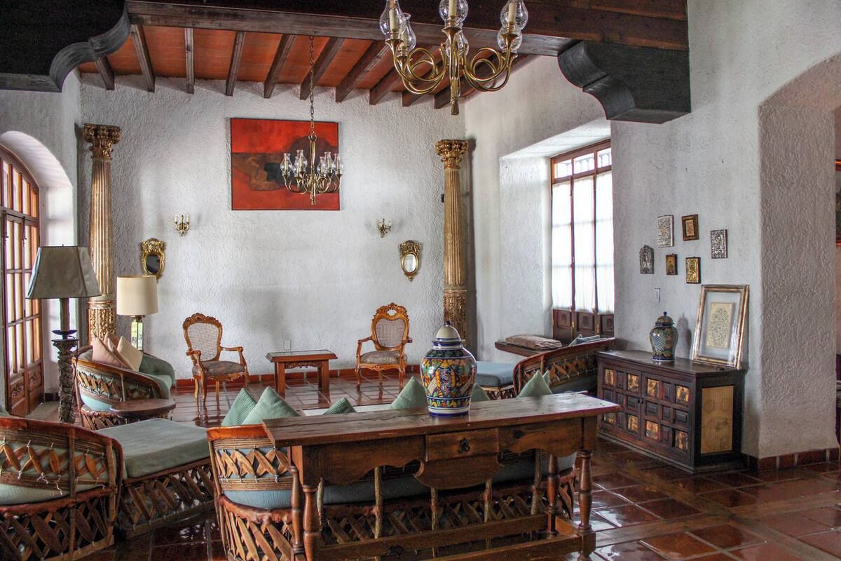 A room with a wooden dining table surrounded by wicker chairs, a chandelier, and a decorative vase.