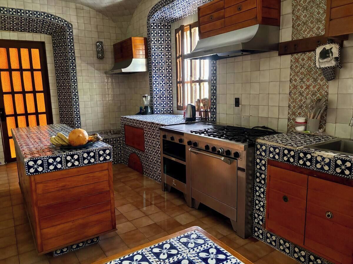 A kitchen with a central island, wooden cabinets, and patterned tile backsplash.