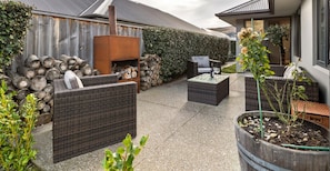 Eine Terrasse mit Korbmöbeln, einem Kaminofen und einem Blumentopf.