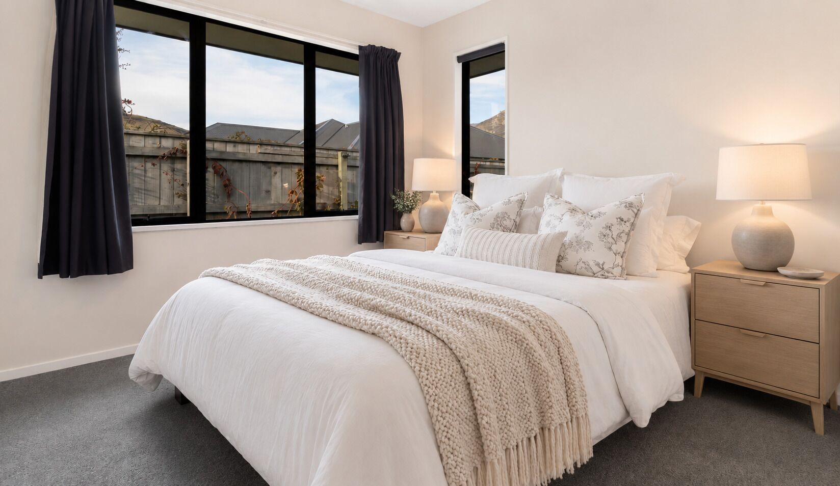 Una camera da letto con un letto, due comodini, una finestra con tende e una lampada.