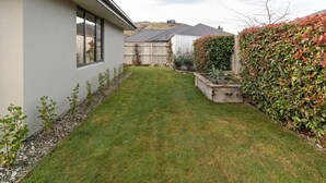 Ein Wohnhaus mit gepflegtem Rasen, Holzzaun und verschiedenen Pflanzen.