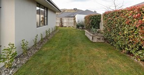 Ein Wohnhaus mit gepflegtem Rasen, Holzzaun und verschiedenen Pflanzen.