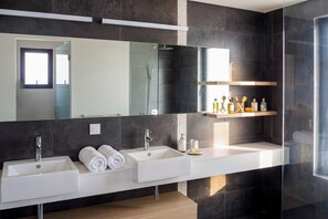 Ein modernes Badezimmer mit zwei Waschbecken, einem großen Spiegel und einer Ablage für Toilettenartikel.