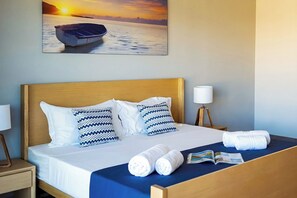 A hotel room with a bed, pillows, a nightstand, a lamp, a towel, and a magazine. - Villa Garden House Gh06, Pool & Holidays, 2 Min To Beach (Mont Choisy)