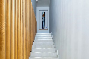 A staircase with wooden paneling on one side and a white wall on the other, leading to a door with a framed picture. - Villa Garden House Gh06, Pool & Holidays, 2 Min To Beach (Mont Choisy)