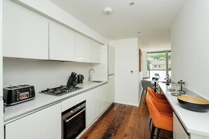 Eine moderne Küche mit weißen Schränken, einem Gaskochfeld, einem Toaster und einer Spüle.