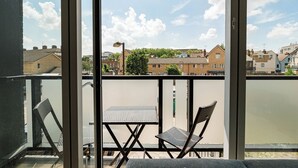 En balkong med ett bord och två stolar, med utsikt över ett bostadsområde med hus och träd.