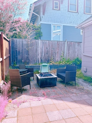 A backyard with a wooden fence, outdoor furniture, and a fire pit.