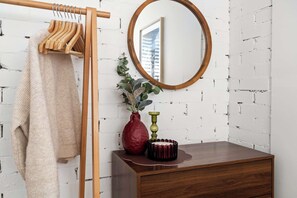 A room with a wooden wardrobe, a mirror, a vase with plants, and a wooden dresser. - Retro Coastal Retreat w Pool and Kings Beach Views (Caloundra Region)