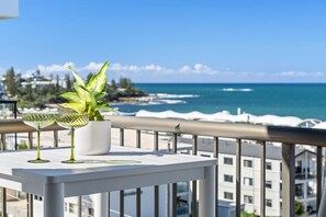 Ein Balkon mit einem Blumentopf und einem Glas auf dem Geländer mit Blick auf die Küste.