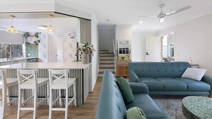 A modern living space with a kitchen, dining area, and a blue sofa. - Spacious 3-Bed Townhouse Near Broadwater (Labrador)