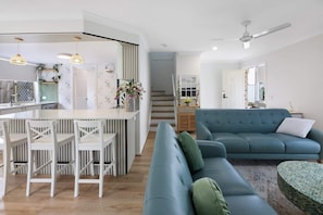 Ein modernes Wohnzimmer mit Küche, Essbereich und einem blauen Sofa.
