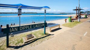 A beach with a sign reading 'IAN DIPPLE LAGOON' and a covered seating area. - Spacious 3-Bed Townhouse Near Broadwater (Labrador)