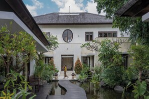 A traditional building with a central courtyard, a wooden walkway, and a water feature. - Beach Club House 7 Bedroom 
Chef+Breakfast+Transfer+Massage+Car&Driver (Canggu)