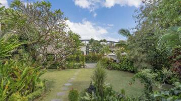 A lush garden with a variety of plants and a stone pathway leading to a building.