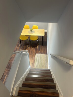 Eine Treppe führt zu einem Essbereich mit einem Tisch und gelben Stühlen.