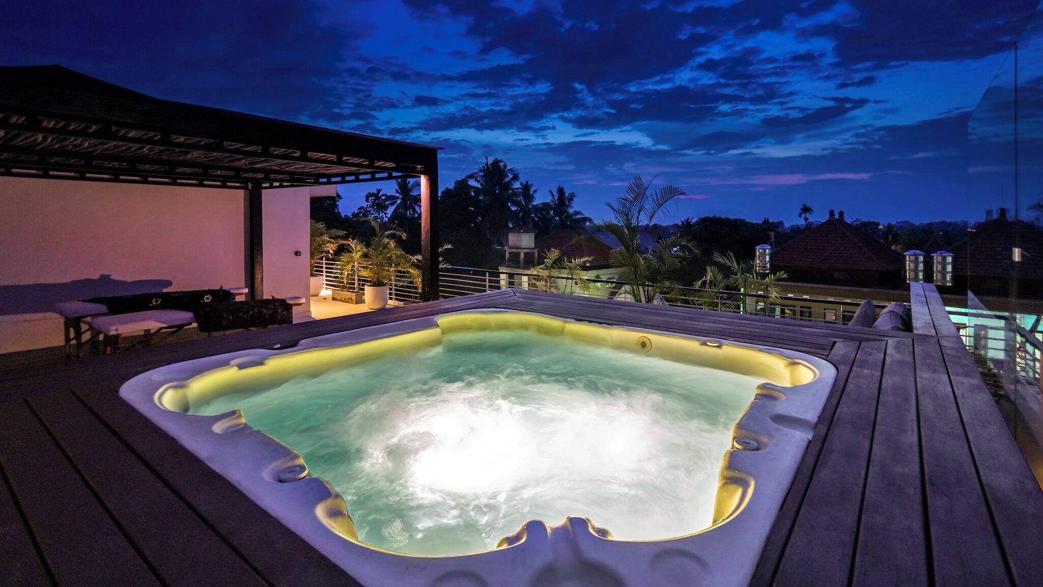 Un bain à remous sur une terrasse en bois, avec vue sur le ciel et les palmiers.