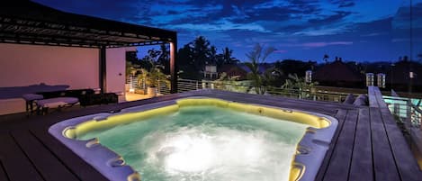 Un bain à remous sur une terrasse en bois, avec vue sur le ciel et les palmiers.
