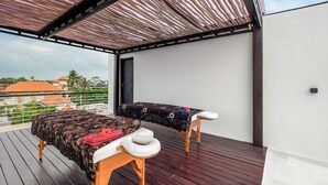 A balcony with a wooden deck, a massage table, and a massage chair. - Helene's House (Ubud, Kabupaten Gianyar)