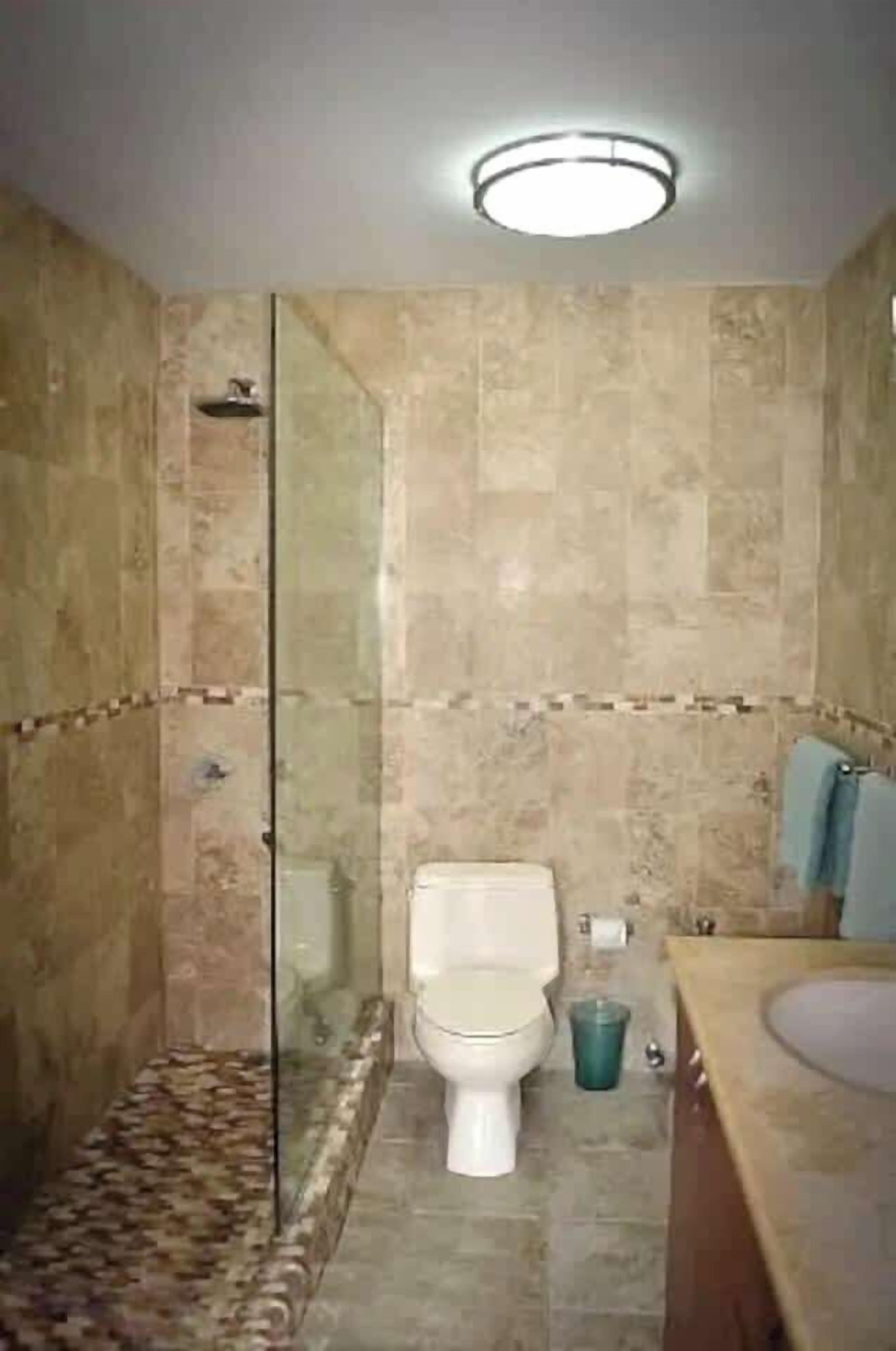 A bathroom with a glass-enclosed shower, a toilet, and a sink.