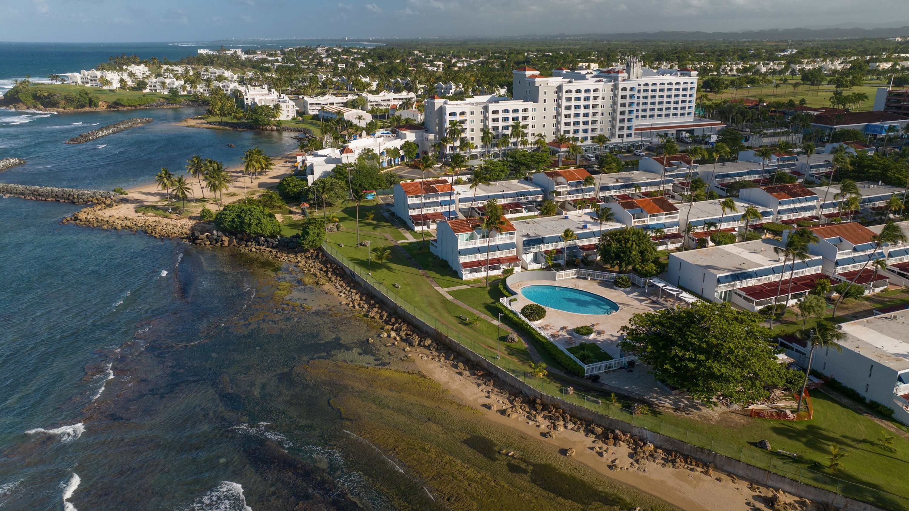 Ein Küstenresort mit mehreren Hotelgebäuden, einem Swimmingpool und direktem Strandzugang.