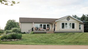 A single-story house with a porch, a small deck, and a front yard. - Enjoy a pleasant 3-bedroom Lake House in Scottville besides St Mary's Lake. (Scottville)