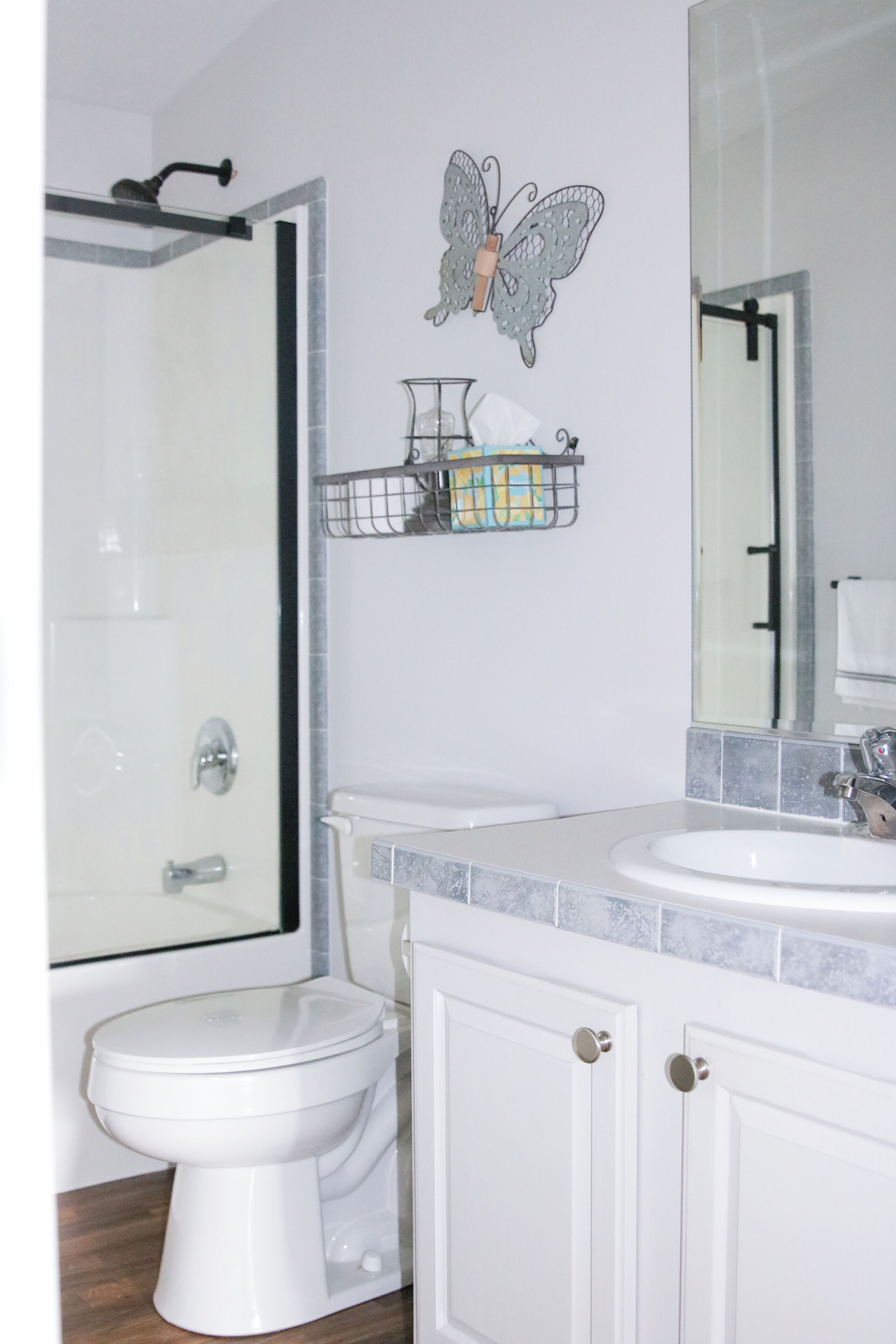 Een badkamer met toilet, douche, wastafel en spiegel.