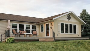 A single-story house with a front porch, a dining table, and four chairs.