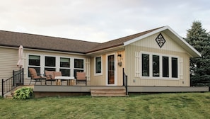 A single-story house with a front porch, a dining table, and four chairs.