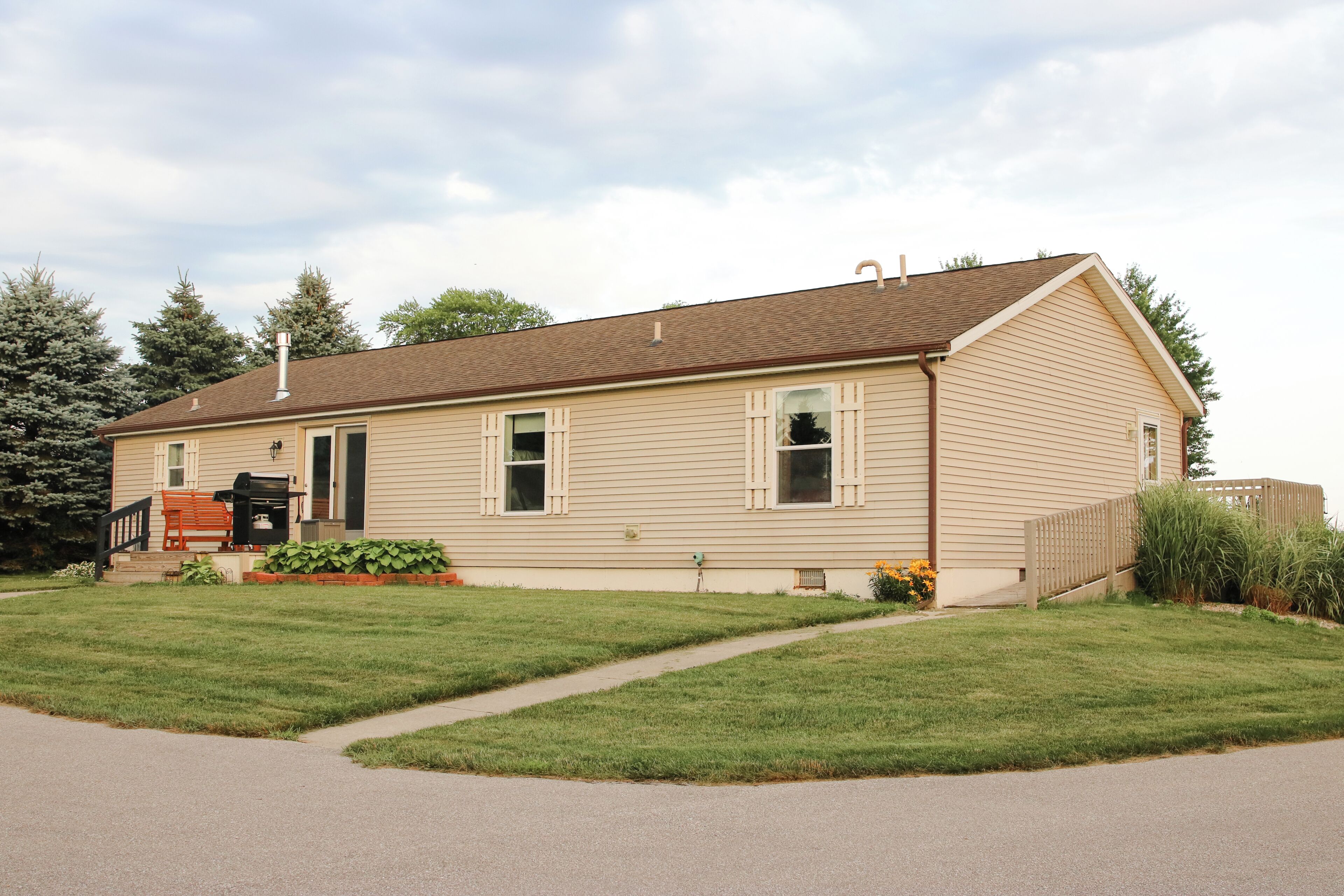 A single-story house with a front porch, a chimney, and a small garden with flowers.