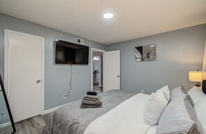 Ein Hotelzimmer mit einem Bett, einem flachbildfernseher an der Wand, einer Tür und einem Spiegel mit Louis Vuitton Logo.