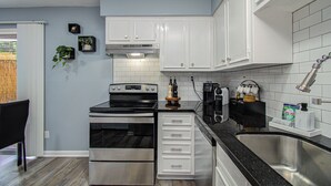 Uma cozinha moderna com armários brancos, eletrodomésticos de aço inoxidável e bancada preta.