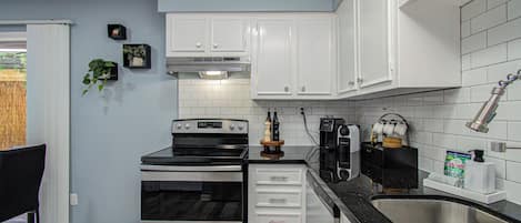 Una cocina moderna con armarios blancos, electrodomésticos de acero inoxidable y encimera negra.