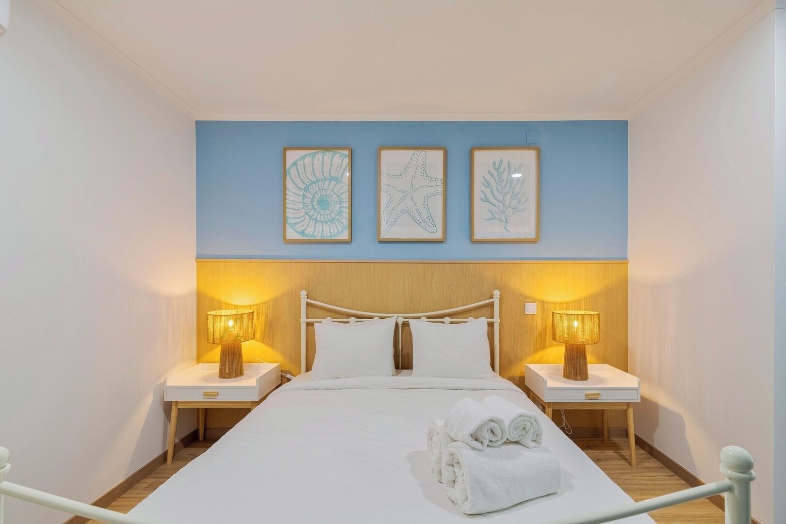 Habitación de hotel con una cama, dos mesitas de noche y tres obras de arte enmarcadas en la pared.