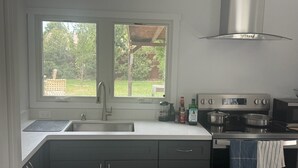 A kitchen with a double sink, stainless steel appliances, and a window overlooking a garden. - Minimalist 1 BR ADU in a pleasant Woodland neighborhood (Woodland)