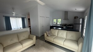 A compact living space with a kitchenette, two sofas, a ceiling fan, and a window with curtains. - Minimalist 1 BR ADU in a pleasant Woodland neighborhood (Woodland)