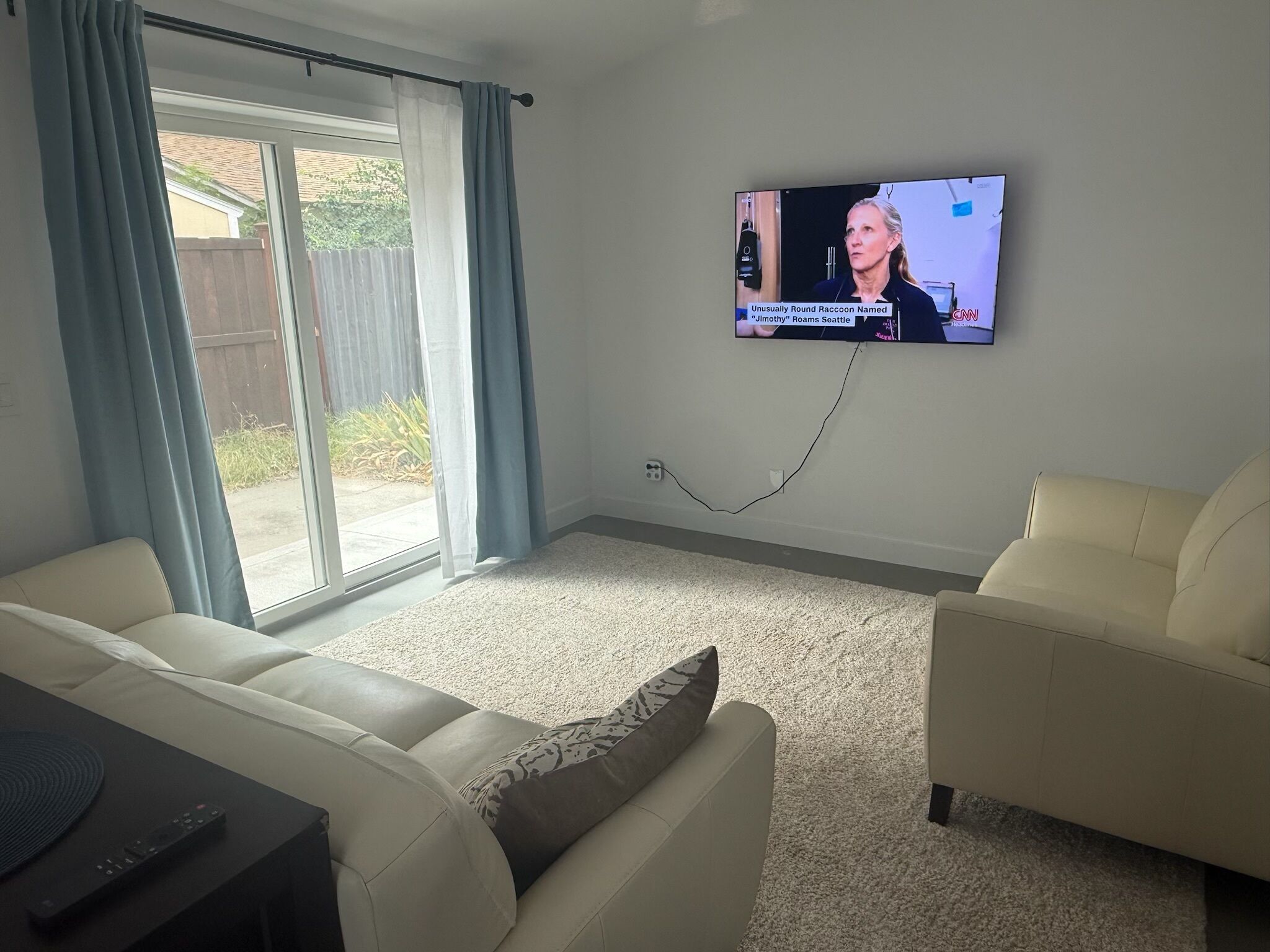 Un salon avec un téléviseur fixé au mur, un canapé et un deuxième espace salon.