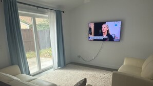 A living room with a television mounted on the wall, a sofa, and a second seating area. - Minimalist 1 BR ADU in a pleasant Woodland neighborhood (Woodland)