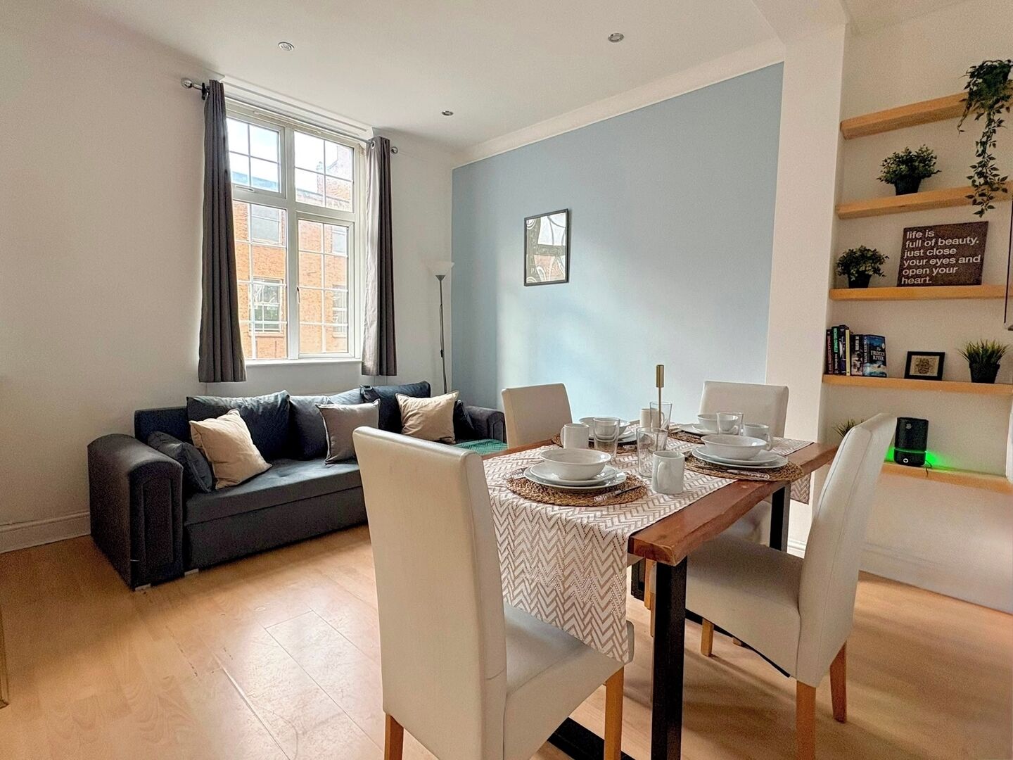 A modern living room with a dining area, a sofa, a coffee table, and a bookshelf.