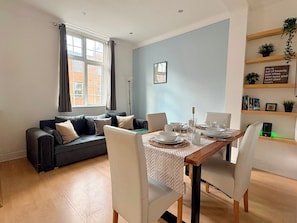 A modern living room with a dining area, a sofa, a coffee table, and a bookshelf. - Islington 2 bedroom terrace Apartment by PrimeCityHosts (London)