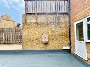 A brick wall with a metal fence, a window, and a small decorative item. - Islington 2 bedroom terrace Apartment by PrimeCityHosts (London)