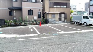Um estacionamento com uma caminhonete branca estacionada em frente a um edifício com várias janelas e entrada gradeada.