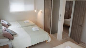 Une chambre d’hôtel avec deux lits, une salle de bain et une armoire.