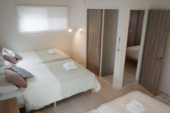 A hotel room with two beds, a bathroom, and a wardrobe.