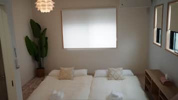 Habitación de hotel con una cama, un ventanal grande, una planta en maceta y una lámpara en el techo.