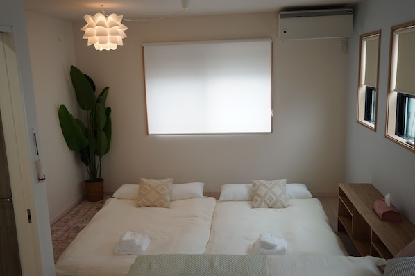 A hotel room with a bed, a large window, a potted plant, and a ceiling light fixture.